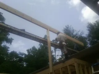 Carpenter setting a ridge beam over a new addition frame — Ice Dam Removal by Roofing Brothers in Culver