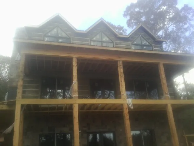 Dormers and porch framing on a large log home under construction — Roof Coating work by our crew in Culver
