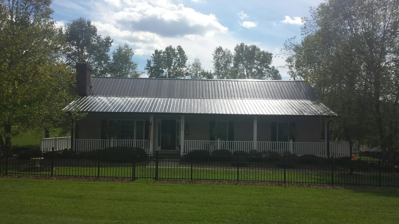 Gray metal roof on a brick ranch with a full width front porch — Gutter Guard Installation work by our crew in Culver
